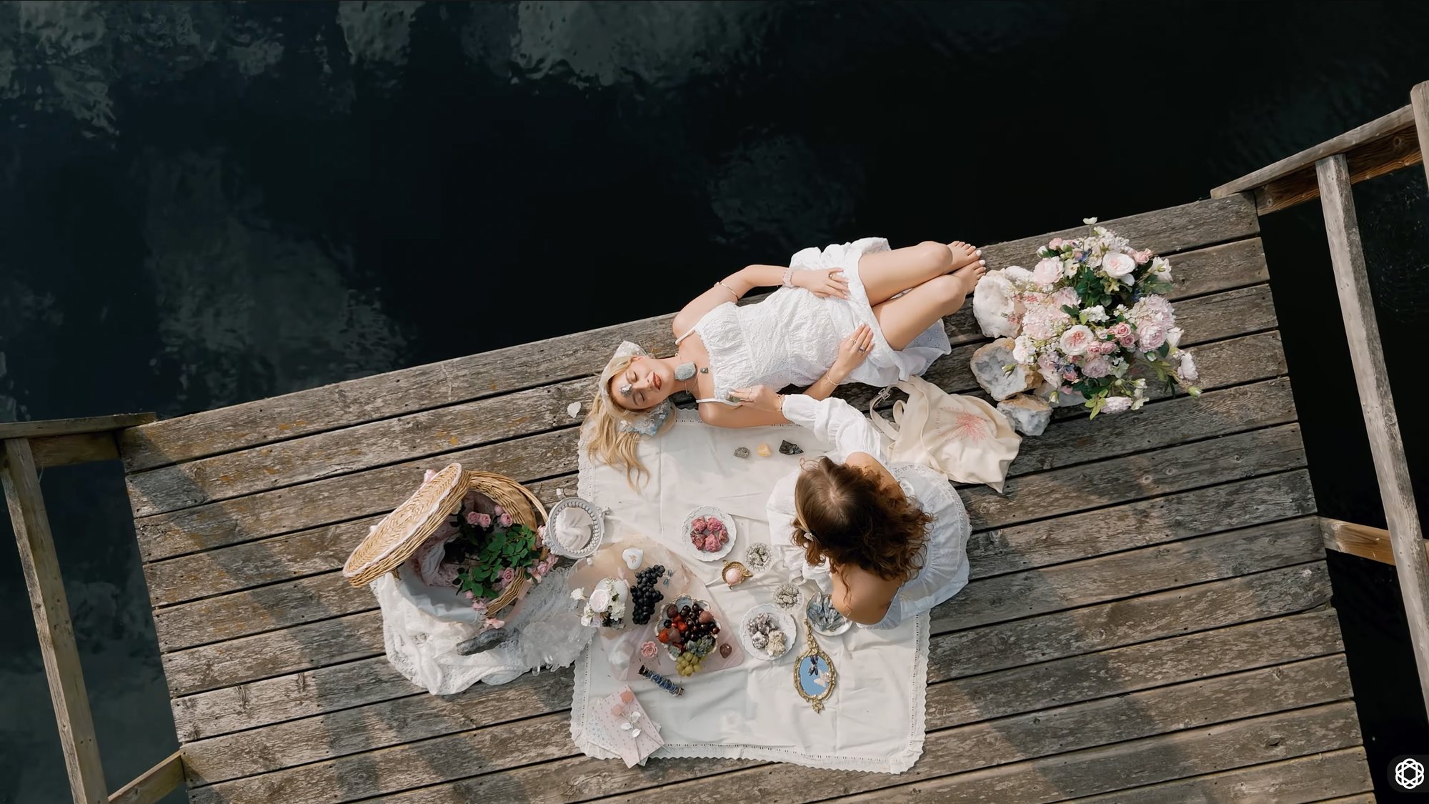 Overhead shot of a bride lying on a wooden jetty, her dress and flowers spread around her